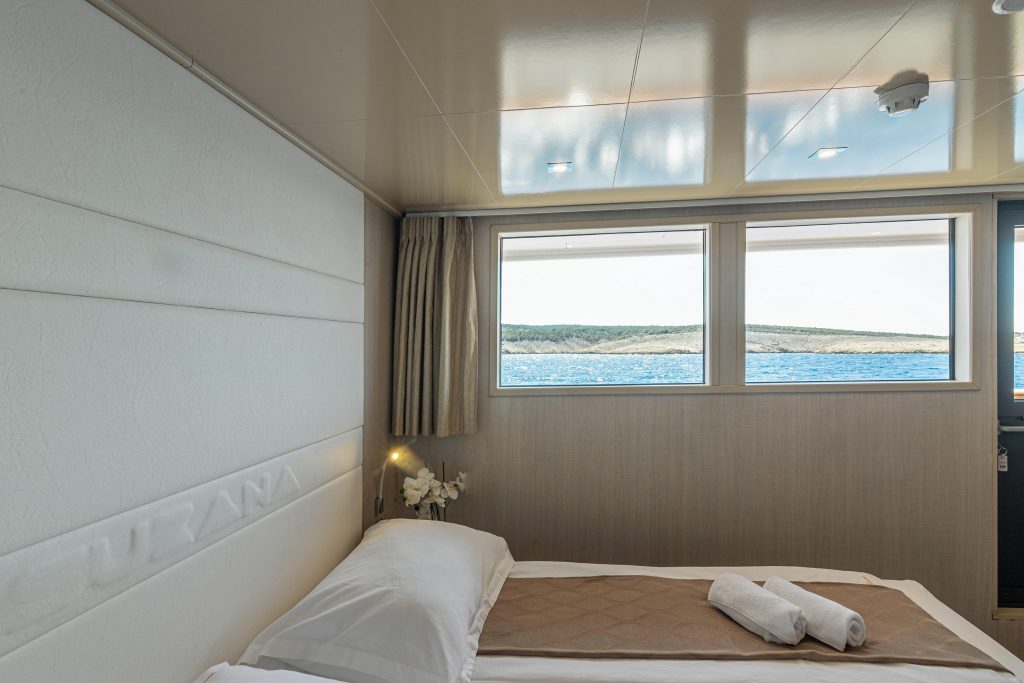 Main deck cabin with a double bed and large windows on a small cruise ship in Croatia