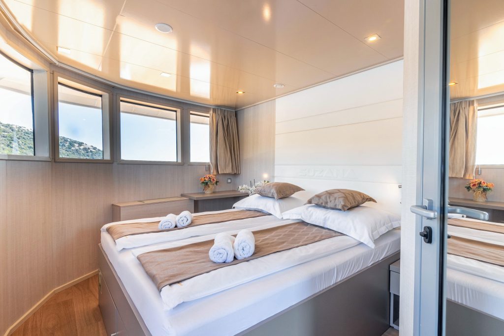 Bright upper deck cabin aboard a Zantium Travel luxury small-ship cruise in Croatia, featuring a double bed, large windows and beautiful Adriatic Sea views.